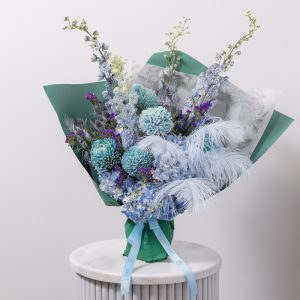 A stunning bouquet of fresh blue flowers with natural feathers and delicate foliage.