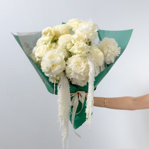 A stunning all-white bouquet of fresh flowers, including peonies, chrysanthemums, and roses.