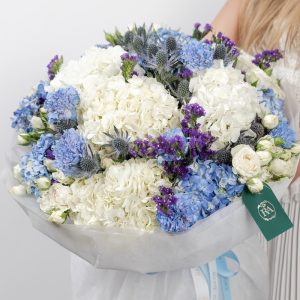 A large, beautiful bouquet of blue hydrangeas and white spray roses with violet accents.
