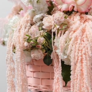 A close-up view of the Blush flower basket, showing the detail of the flowers, feathers, and preserved amaranthus.