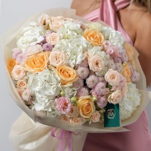 A close-up of a fresh bouquet with peach avalanche roses and a mix of soft pink and white flowers.