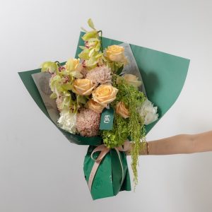 A stunning bouquet of fresh flowers in earthy tones, including orchids, chrysanthemums, and peach roses.