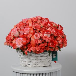 A stunning basket of red, orange, and pink roses, with lush green foliage.