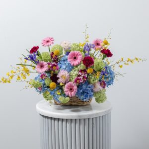 A stunning, vibrant flower basket with a mix of colorful fresh flowers, including blue hydrangeas and pink gerberas.