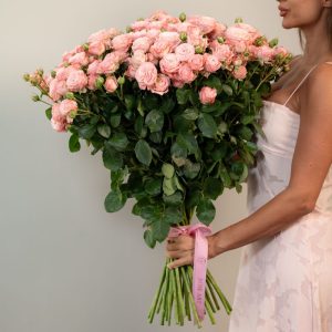 A close-up detail shot of the Madam Bombastic spray rose heads, highlighting the multiple blooms on each stem and their soft pink color.