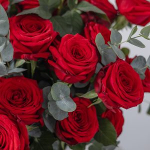 A close-up view of the luxury Aroma flower box, highlighting the red roses and green eucalyptus.