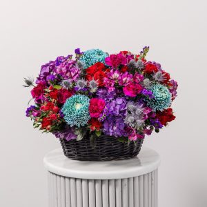 A stunning arrangement of dark purple and burgundy flowers in a wicker basket.