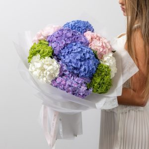 A large, beautiful bouquet of mixed-color hydrangeas, including blue, pink, and white.
