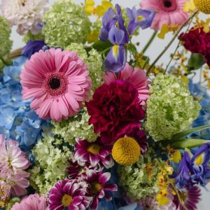 A close-up view of the luxury Joyful flower basket, showing the detail of the craspedia and iris blooms.