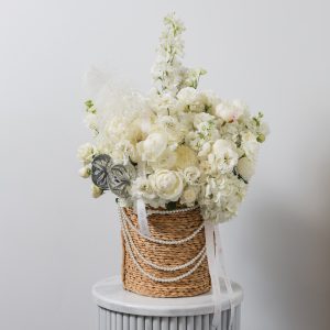 A stunning white flower basket arrangement with a mix of fresh blooms and silver accents.