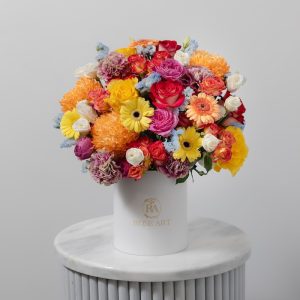 A colorful flower box with mixed flowers in sunset hues, including pink, orange, and yellow blooms.