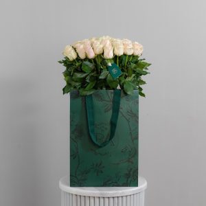 A large bunch of Talea roses arranged in a tall, elegant glass vase.