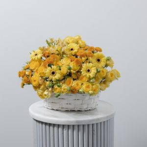 A beautiful basket arrangement of fresh yellow flowers, including roses and other blooms.