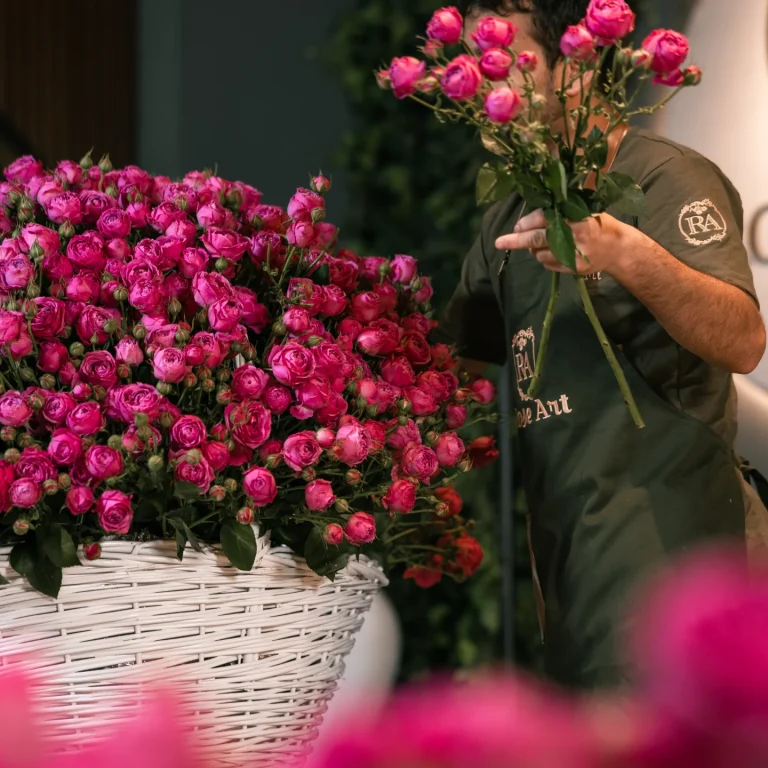 Rose Art Flowers team member preparing red rose basket uniform Dubai UAE