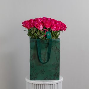 A large bunch of "All For Love" roses arranged in a tall, elegant glass vase.