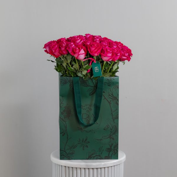 A large bunch of "All For Love" roses arranged in a tall, elegant glass vase.