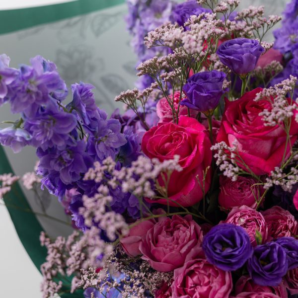 A close-up side view of the Art of Purple bouquet, showing the detail of the delphiniums and roses.