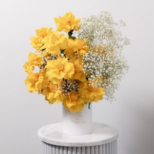 A luxurious box arrangement of yellow roses and white gypsophila flowers.