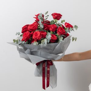 A luxurious bouquet of red Naomy roses mixed with aromatic eucalyptus leaves.