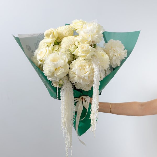 A stunning all-white bouquet of fresh flowers, including peonies, chrysanthemums, and roses.