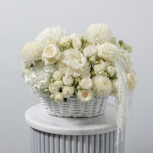 A stunning all-white floral basket of fresh flowers, including peonies, chrysanthemums, and roses.