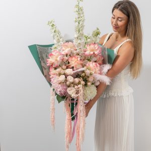 A close-up view of the luxury Blush bouquet, showing the detail of the flowers, feathers, and amaranthus.