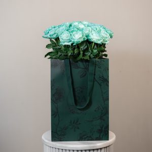 A large bunch of Tiffani blue roses arranged in a tall, elegant glass vase, ready to be displayed in a home or office setting.