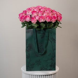 A large bunch of Candy Avalanche roses arranged in a tall, elegant glass vase.