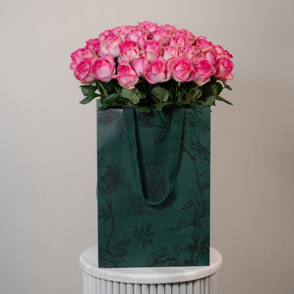 A large bunch of Candy Avalanche roses arranged in a tall, elegant glass vase.