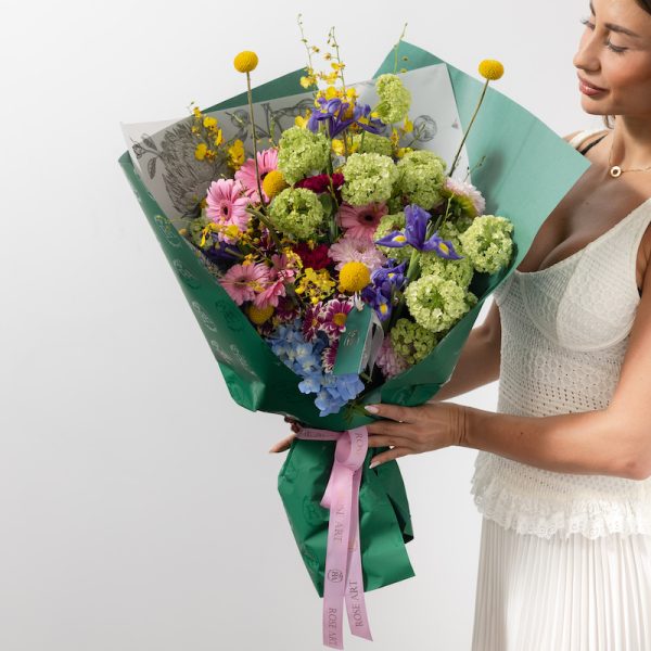 A close-up view of the luxury Joyful bouquet, showing the detail of the craspedia and iris blooms.