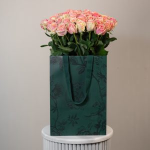 A large bunch of Fiesta roses arranged in a tall, elegant glass vase.