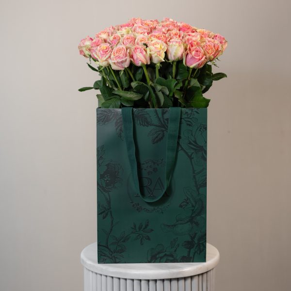 A large bunch of Fiesta roses arranged in a tall, elegant glass vase.