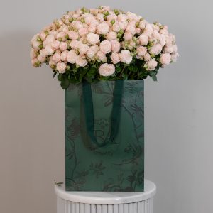 A large bunch of Bombastic spray roses arranged in a tall, elegant glass vase, ready to be displayed in a home or office setting.