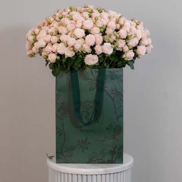 A large bunch of Bombastic spray roses arranged in a tall, elegant glass vase, ready to be displayed in a home or office setting.