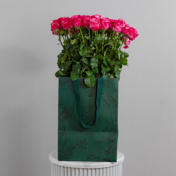 A large bunch of Deep Water roses arranged in a tall, elegant glass vase, ready to be displayed in a home or office setting.