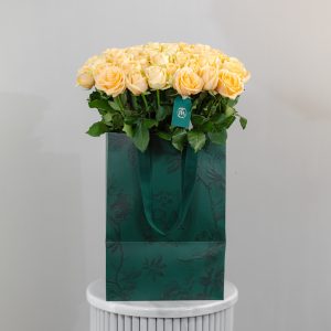 A large bunch of Peach Avalanche roses arranged in a tall, elegant glass vase.