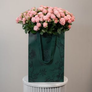 A large bunch of Madam Bombastic spray roses arranged in a tall, elegant glass vase, ready to be displayed in a home or office setting.