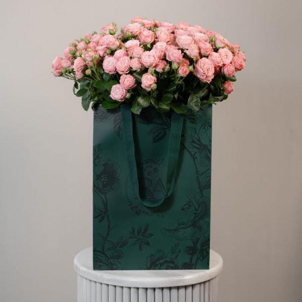 A large bunch of Madam Bombastic spray roses arranged in a tall, elegant glass vase, ready to be displayed in a home or office setting.