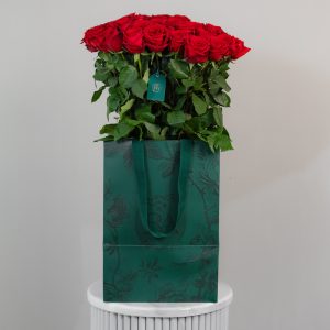 A large bunch of Red Naomi roses arranged in a tall, elegant glass vase.