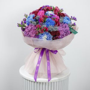 A close-up side view of the Midnight Bloom bouquet, showing the mix of dark-toned blooms.