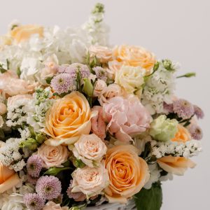 A close-up side view of the Soft Serenade basket, showing the detail of the peach gerbera and delicate roses.