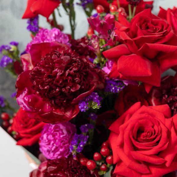 A close-up side view of the Red Velvet bouquet, showing the detail of the red peonies and roses.