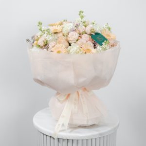 A close-up side view of the Soft Serenade bouquet, showing the detail of the peach gerbera and delicate roses.