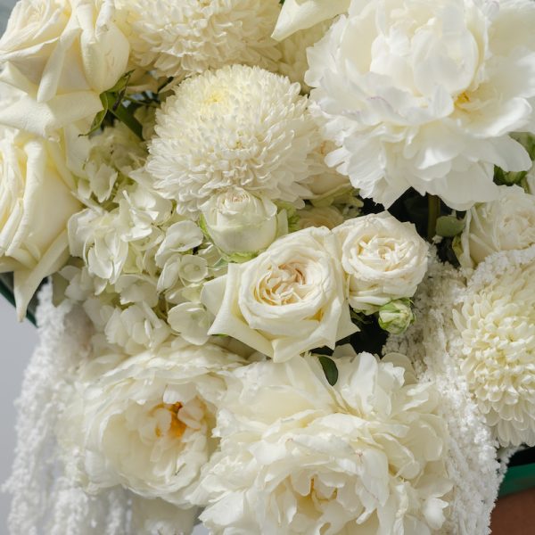 A close-up side view of the Art of White bouquet, showing the detail of the peonies and amaranthus accents.