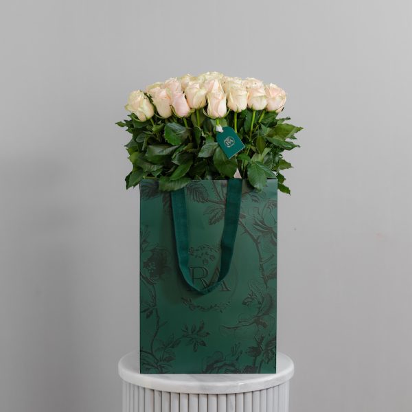 A large bunch of Talea roses arranged in a tall, elegant glass vase.